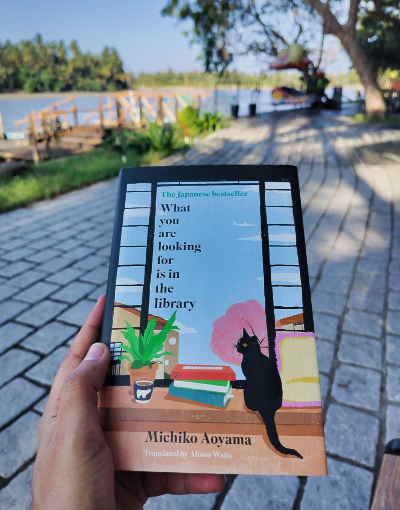 Holding the book What You Are Looking For Is in the Library by Michiko Aoyama