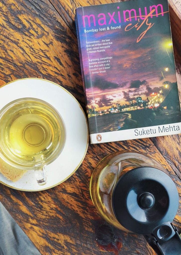 Suketu Mehta's book Maximum City placed on a table alongside a cup of green tea