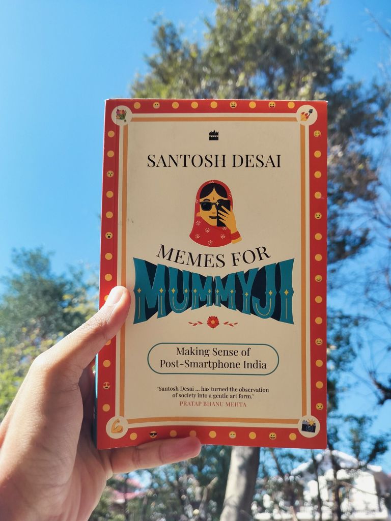 Holding Santosh Desai's book Memes for Mummyji with sky and a tree in the background