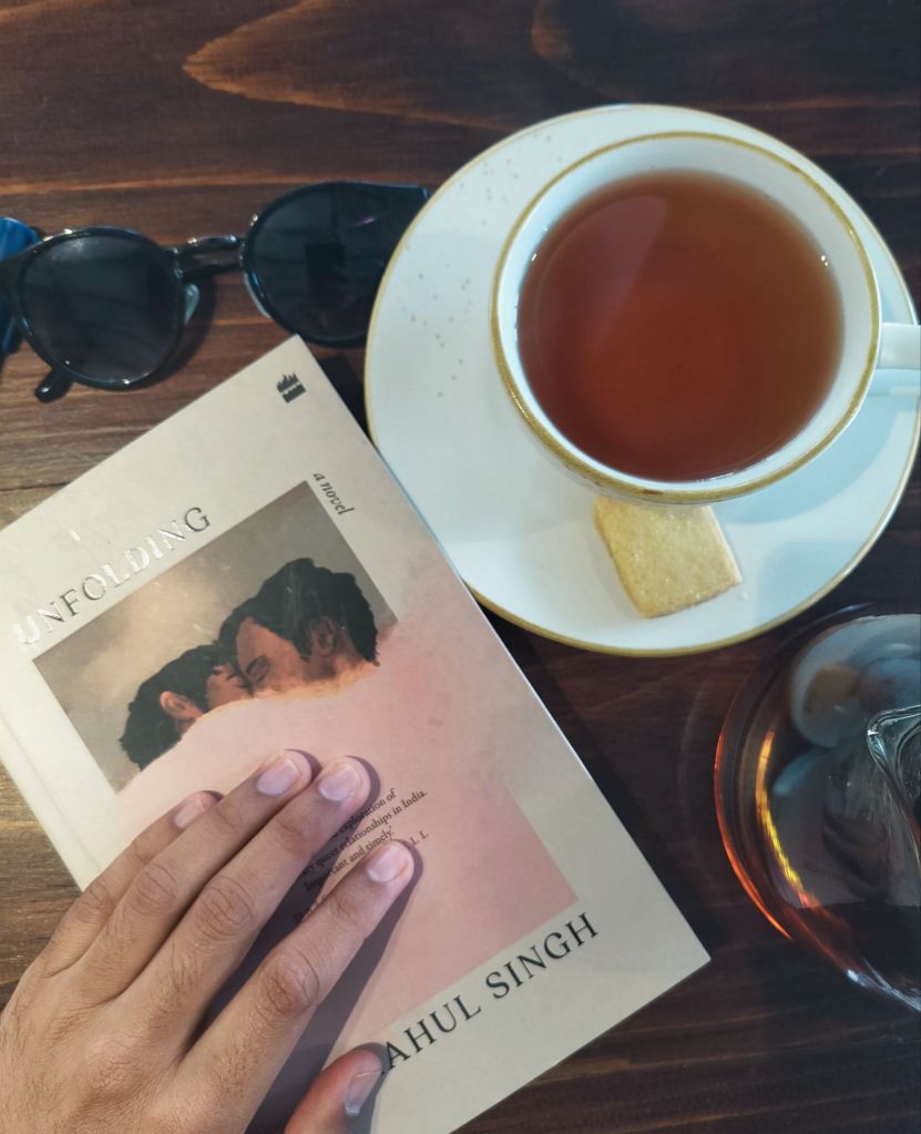 The book Unfolding by Rahul Singh placed on a table alongside a cup of tea
